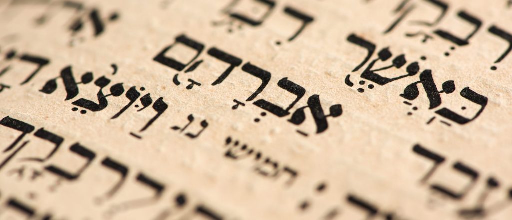 Closeup of hebrew word Abraham in Torah page. Selective focus. Banner.